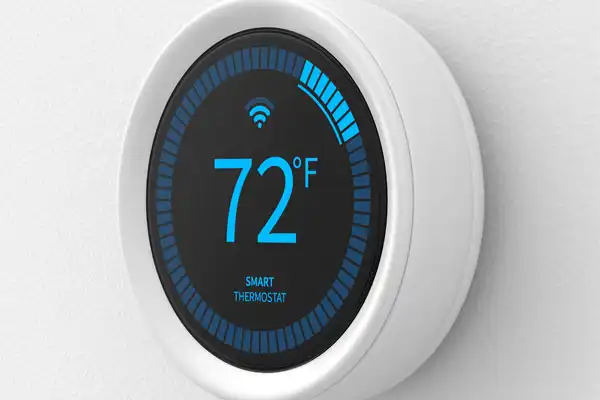 A smart thermostat on a wall displays a temperature of 72°F with a Wi-Fi symbol above the number.